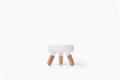 A small modern stool with a white rounded rectangular seat and three tapered natural wood legs, centered on a clean white background.