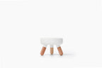 A small modern stool with a white rounded rectangular seat and three tapered natural wood legs, centered on a clean white background.