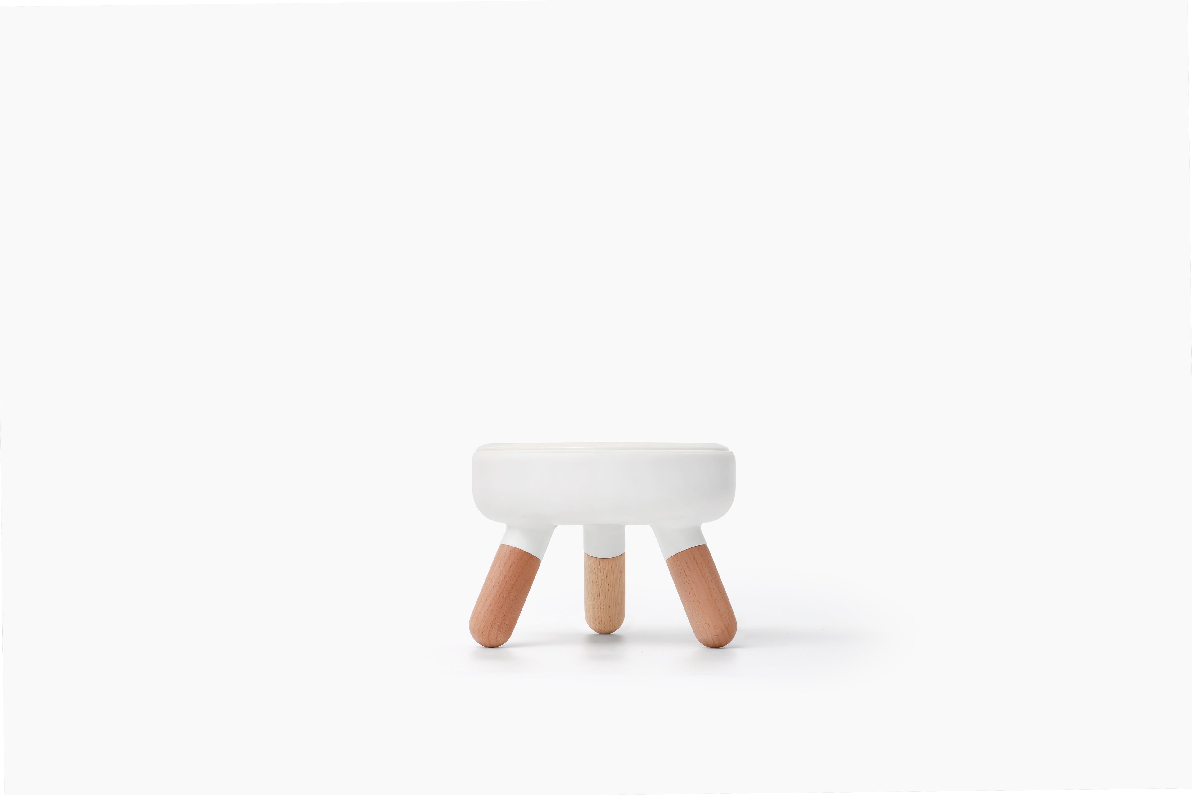 A small modern stool with a white rounded rectangular seat and three tapered natural wood legs, centered on a clean white background.