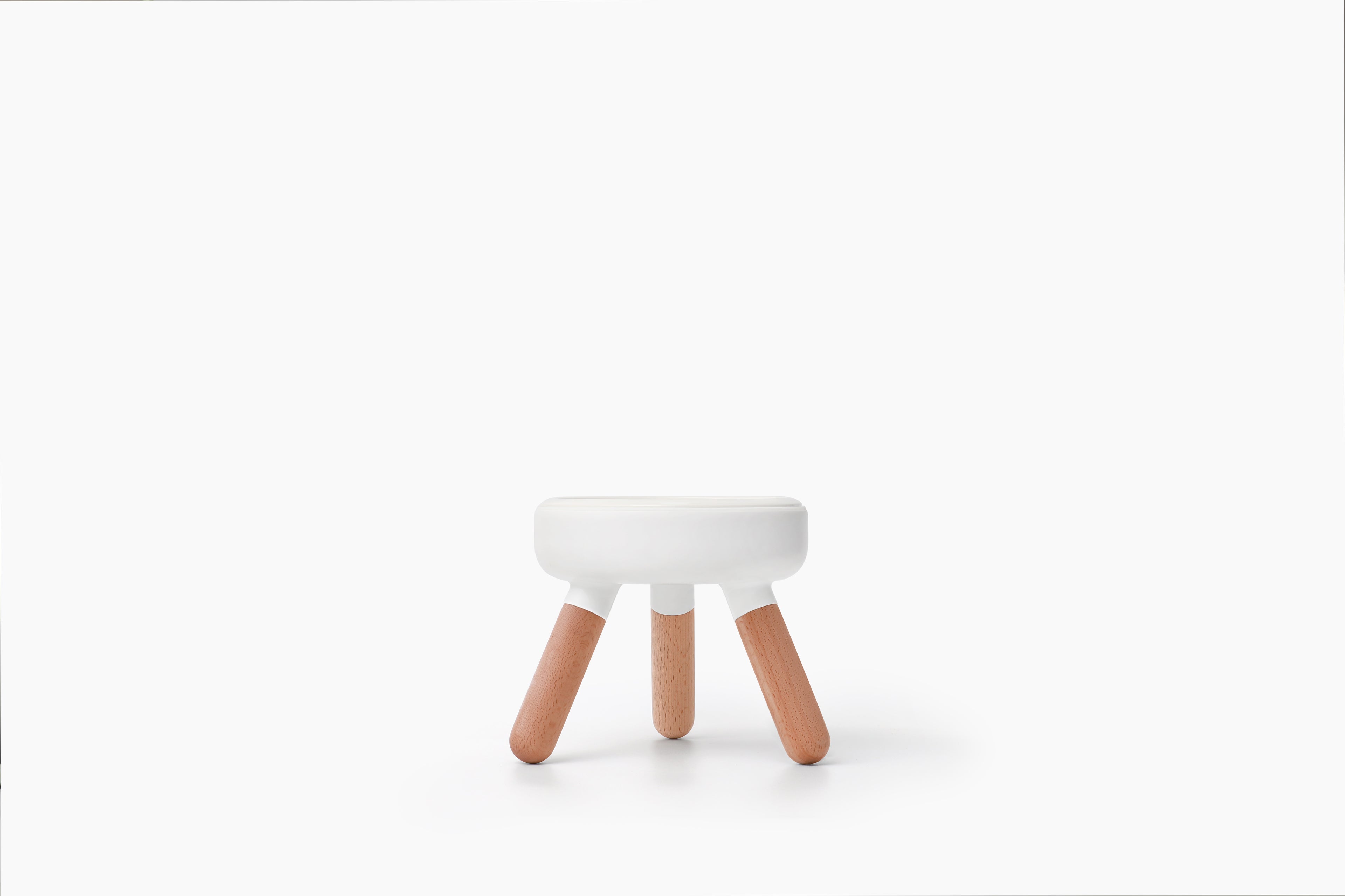 A small modern stool with a white circular seat and three light natural wood legs, centered on a clean white background.